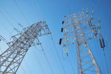Supports high-voltage power line against a clear blue sky. Wires or cables are connected through...