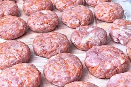 Fresh cutlets of beef and pork lie on a wooden Board covered with a film.の写真素材