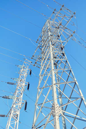 Supports high-voltage power line against a clear blue sky.の写真素材