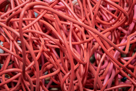 Tangled lump or pile of red electrical patch cords. The disorder and chaos from the wastes or scraps...