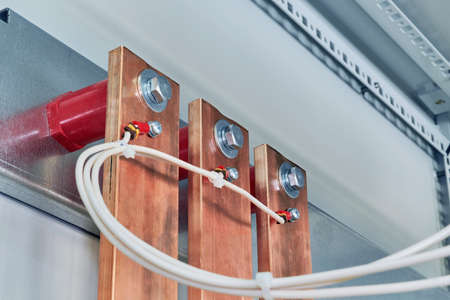 Electrical wires are connected to copper busbars. Busbars are fixed to the circuit Board through red...