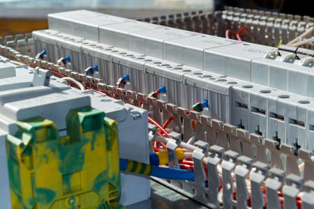 Modern modular contactors and circuit breakers with electrical wires connected to them. Assembly of the electric Cabinet in the workplace. The wires are laid in perforated cable channels.の写真素材