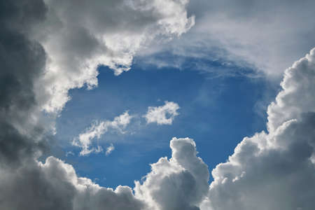 Stormy Cumulus clouds are surrounded by a clear blue sky. In the middle of an oval of clear sky and hovering around all sides of the rain clouds. Meteorology, weather forecast.の写真素材
