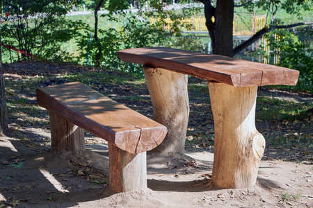 Table and bench of wooden logs and boards in the Park on the shore of the lake or river. Bright, warm Sunny day. Outdoor recreation in nature. Autumn, are the leaves.の写真素材