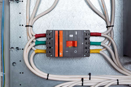 One large power circuit breaker in the electrical Cabinet. Many cables or wires are connected to the switch. Big bunch of wires. Distribution of electricity in networks. Reliable protection.の写真素材