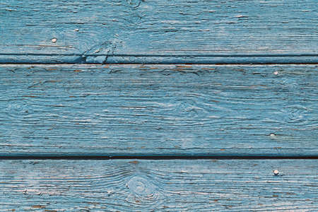The surface of old wooden boards painted by blue paint. The paint faded and disappeared in the open air. The paint swelled and burst, covered with small cracks. Background, backdrop, Wallpaper.の写真素材