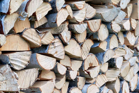 Large pile or stock of firewood for heating furnace. Logs and logs of birch. The log is split in half. Slice as a circle, semicircle. Background, backdrop, texture. Side view. Shallow depth of field.の写真素材