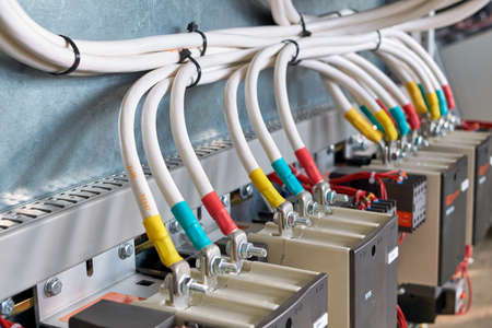 A large bundle of electrical cables or wires connected to contactors. High-power magnetic starters. Connection using a bolted connection. Large electrical Cabinet. Modern and reliable equipment.の写真素材