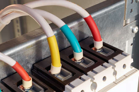 Several wires or cables are connected to the industrial circuit breaker. Connection of a large switch in the electrical Cabinet. The wires are marked with color. Power distribution technologies.の写真素材