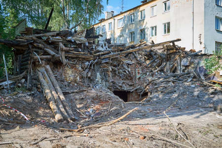 Demolition or disassembly of an old burnt wooden house. In the middle of the entrance to the basement. In the background is an apartment building. For the construction of a new house.の写真素材