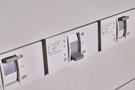 Three industrial circuit breakers are arranged in a row in an electrical Cabinet. The switch in the...