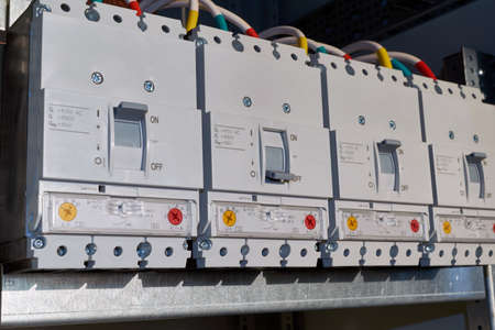 Four power circuit breakers are fixed in the electrical Cabinet in line. Modern and reliable switches for power distribution in buildings. Technologies of production and connection of wires, cables.の写真素材