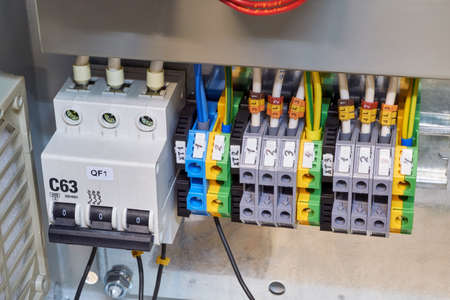 Modular circuit breaker and a number of terminals in the electrical Cabinet. Electrical wires or cables are connected to the switch and terminals. Reliable and modern power distribution.の写真素材