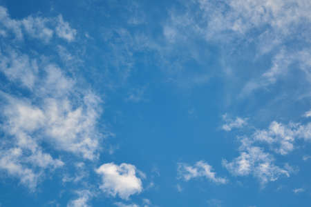 Small Cumulus and Cirrus clouds diverge from the center in different directions. In the middle is the empty space of a clear blue sky. Background, backdrop. Meteorology, weather forecast.の写真素材