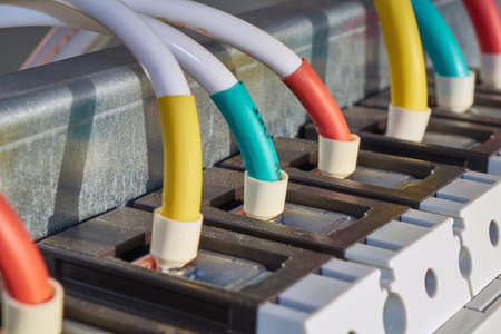 Several wires or cables are connected to the industrial circuit breaker. Connection of a large switch in the electrical Cabinet. The wires are marked with color. Power distribution technologies.の写真素材