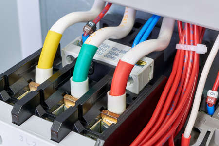 Three cables or wires are connected to a powerful electrical contactor. The magnetic starter is fixed in the electrical Cabinet. Reliable, modern connection. To the right a bundle of flexible wires.の写真素材