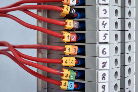 A number of red electrical wires or cables are connected to the through terminals. On wires and terminals marking in the form of numbers. Convenient connection of electrical cabinets.の写真素材