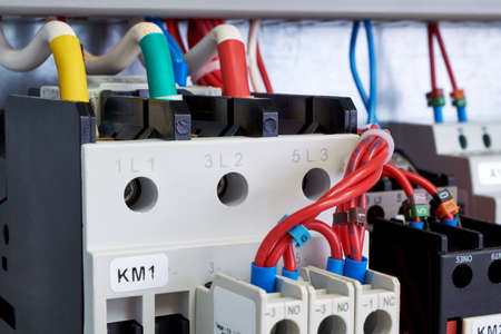Electrical cables and wires are connected to electrical equipment. Front additional contacts are fixed on magnetic starters. Modern equipment in the electrical Cabinet. Color and digital marking.の写真素材