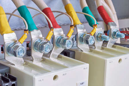 Connection of electrical cables and wires to industrial magnetic starters. Cables are marked with color. Bolted connection with nut. Modern production of electric cabinets. Electricity distribution.の写真素材