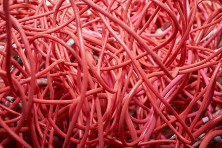 A bunch of highly entangled red electrical wires. Confusion, chaos, disorder. Waste or wire scraps are very much intertwined. Flexible stranded wires.の写真素材