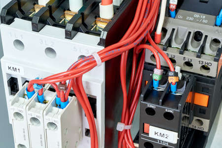 Electrical wires or cables are connected to magnetic starters or contactors. On the front of the contactor front mounted auxiliary contacts. Wiring by scheme or project. Modern technology.の写真素材