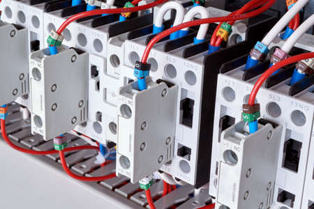 Several electric magnetic starters or contactors with additional contacts. Contactors are arranged in a row with wires connected to them. Connection of wires according to the scheme or project.の写真素材