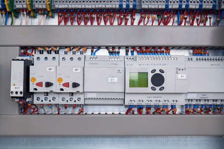 Phase control relay, motor protection circuit breaker, power supply and controller with input and output expansion unit in electrical Cabinet. Many wires connected to the scheme.の写真素材