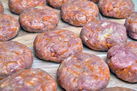 Several raw cutlets of beef and pork lie on a wooden Board. Home-made cutlets with carrots, onions and spices. Tasty and healthy food. Cutlets in the form of an oval or flat cakes.の写真素材