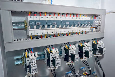 Series of Fuse holders, contactors or magnetic starters with front additional contacts, cylindrical capacitors in the electric reactive power compensation Cabinet. Wires are connected to the project.の写真素材