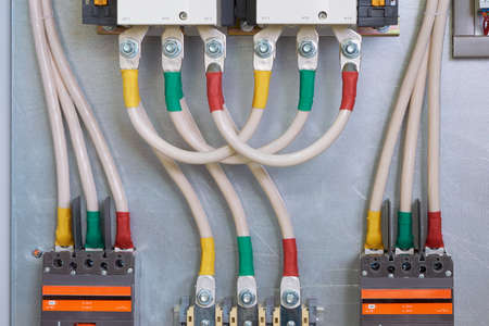 Connecting cables or wires to an industrial contactor or starter, circuit breakers and bolt-through terminals in an electrical Cabinet. The cables are connected in series and bent by a loop.の写真素材