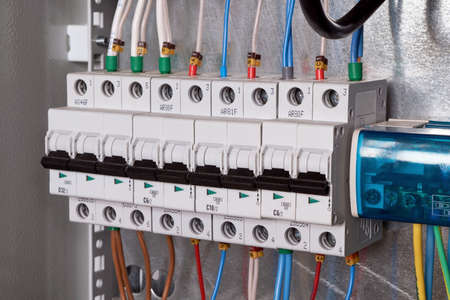 A number of electric modular circuit breakers and a cross-module for the distribution of electricity to multiple consumers in an electrical Cabinet. The wires are connected to the switches.の写真素材