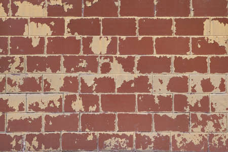 The surface of the wall of the building is lined with rectangular tiles. The yellow paint on the tile was peeling and peeling from time to time. Tiles red-brown. Background, backdrop, texture.の写真素材