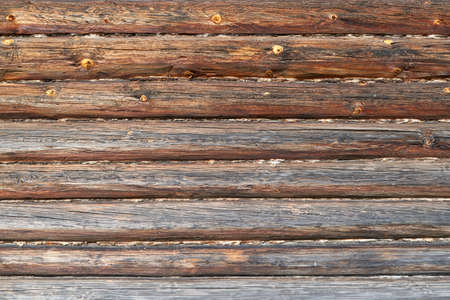 The surface of the wall or frame wooden house of logs brown. Seams between logs are compacted with tow, moss or wool. The logs have a wave pattern and cracks. Background, backdrop or Wallpaper.の写真素材