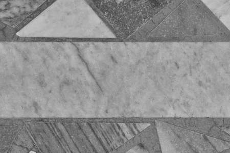 The surface of the floor or wall is made of marble or granite tiles. In the center of the tile rectangular shape. Around the rectangle, the tiles are triangular in shape. Monochrome image.の写真素材
