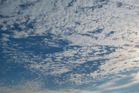 Many, many little broken clouds in the blue sky. Loose little Cumulus clouds filled the sky in streaks. Background or backdrop. Clouds float over the horizon.の写真素材