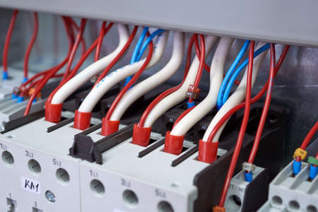 Many electrical wires or cables are connected to magnetic starters. Electrical equipment in the electrical Cabinet. Manufacture, repair, adjustment, automation. Shallow depth of field.の写真素材