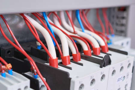 Many electrical wires or cables are connected to magnetic starters. Electrical equipment in the electrical Cabinet. Manufacture, repair, adjustment, automation. Shallow depth of field. Left-side view.の写真素材