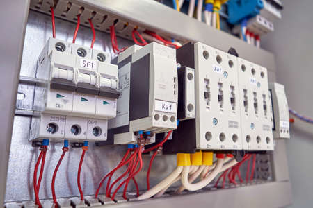 The circuit breaker, phase control relays and power contactors are arranged in a row in the electrical Cabinet. Marked cables and wires are connected to the switch, relays and contactors.の写真素材