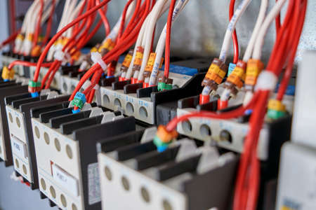 Many electrical wires or cables are connected to contactors and additional contacts in the electrical Cabinet. The wires are marked with numbers and letters. Low depth of field.の写真素材