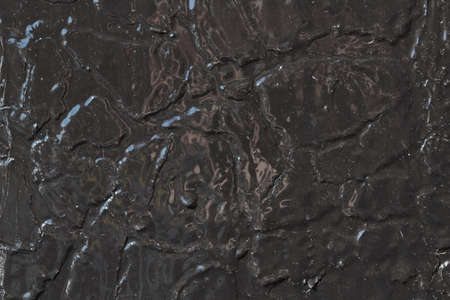 Wall surface painted with black oil paint. Under the new paint, the old paint is cracked. The surface is smooth with streaks and spots. Background, texture. Backdrop.の写真素材