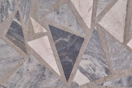 A flat floor or wall surface with triangular granite tiles. The tiles are laid out in a mosaic in a chaotic order. Triangles are large, small, and medium in size. Texture, background, and backdrop.の写真素材