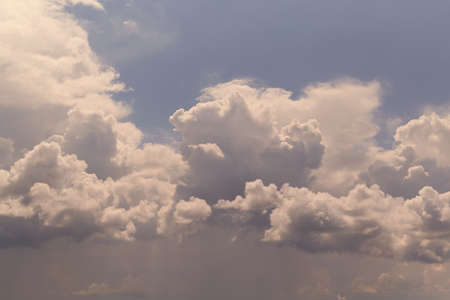 Huge storm clouds are moving against the blue sky. Below, under dark clouds, it is raining. On top of large Cumulus clouds. Background, backdrop.の写真素材