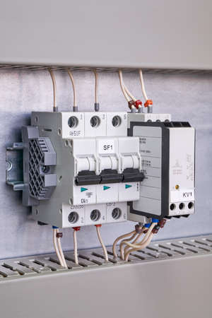 Modular circuit breaker, phase control relay and a stop that locks them on a rail in the electrical Cabinet. Wires are connected to the switch and relay. The wires are marked.の写真素材