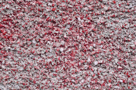 Many small pieces of red glass are glued to the surface of the wall. Pieces of different shapes and sizes are filled with construction glue. Decorating the wall of the house from the outside.の写真素材