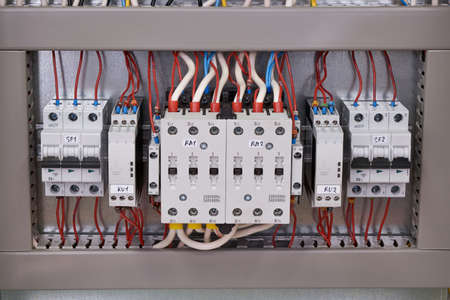 Two contactors with mechanical interlocking between them, two phase control relays and two circuit breakers in the electrical Cabinet. Cables and wires are connected to the electrical equipment.の写真素材