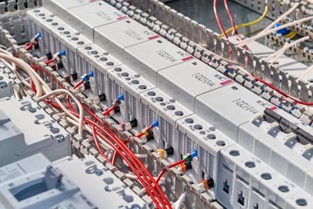 Red electrical wires are connected to modular contactors or starters in the electrical Cabinet. The wires and cables are laid in the cable channel. Professional production of electrical cabinets.の写真素材