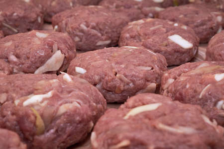 Several raw cutlets of minced meat and beef and pork lie in rows. Cabbage and garlic are added to the minced meat. Home cooking useful and healthy food.の写真素材