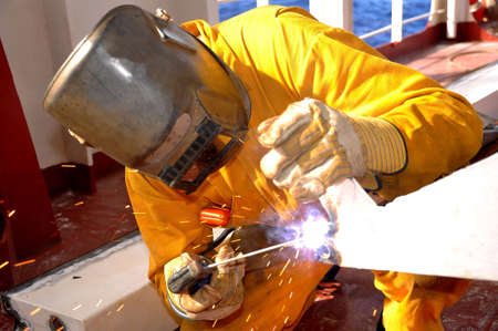 welder works on deck of ship