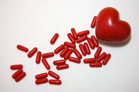 Red pills and a red heart on a white backgroundの写真素材