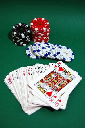 Casino tokens with a deck of cards on a green tableのeditorial素材